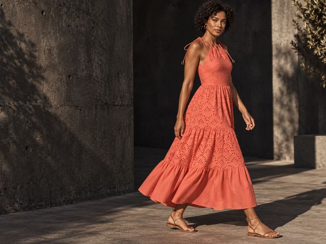 A coral eyelet maxi dress on a sunlit terrace, AI-generated model photography